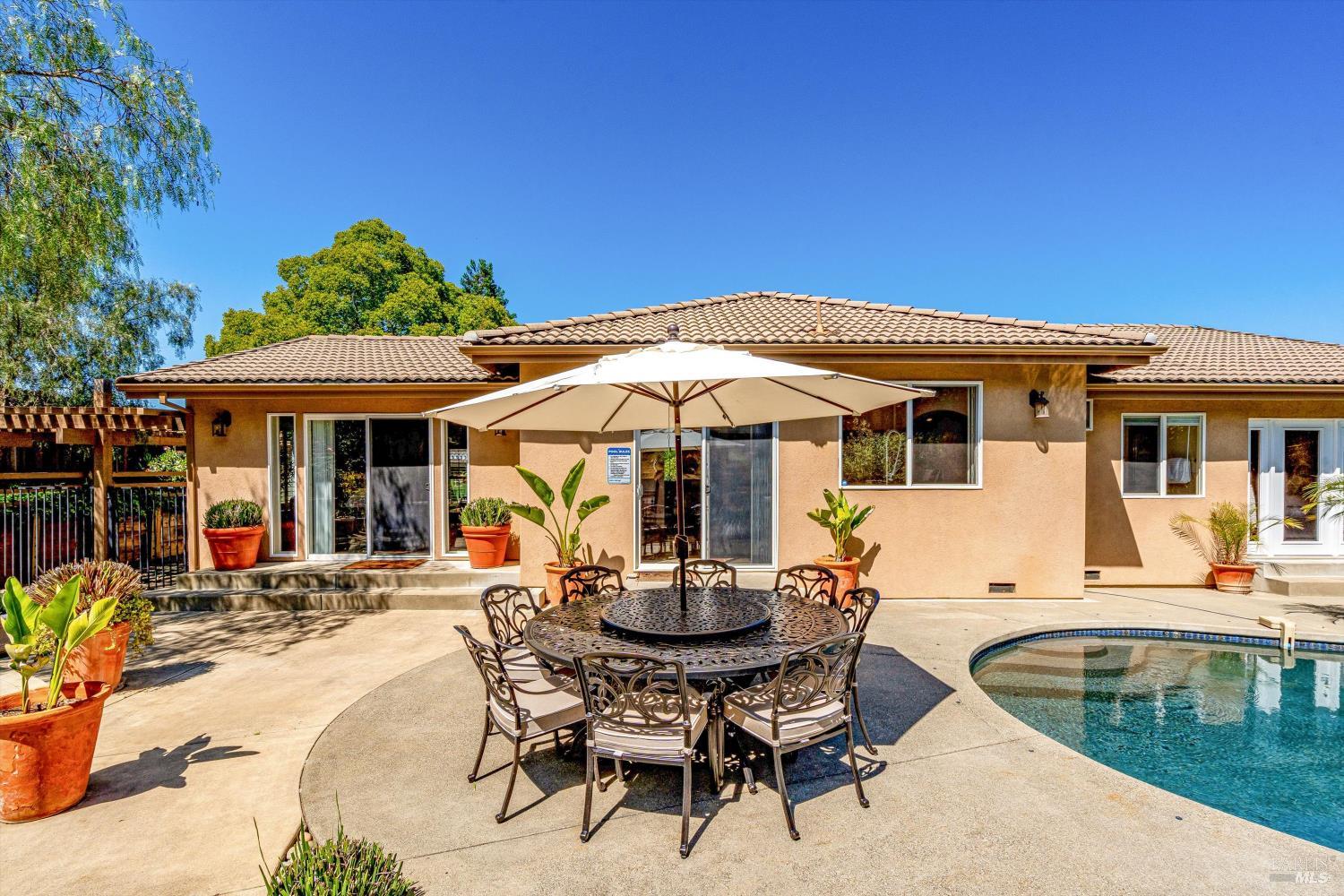 A single-story tile-roofed home with a dining patio beside its pool in Napa's Browns Valley